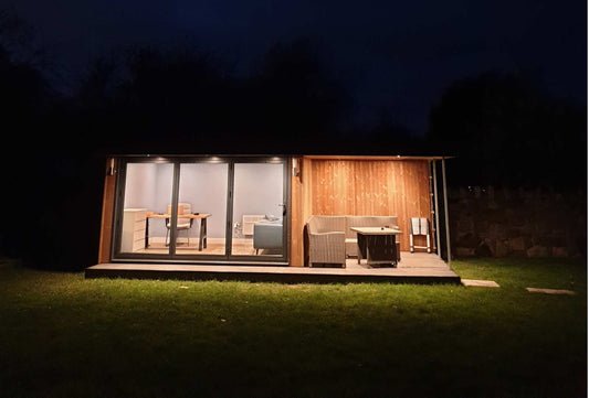 A night time view of garden room office with side canopy