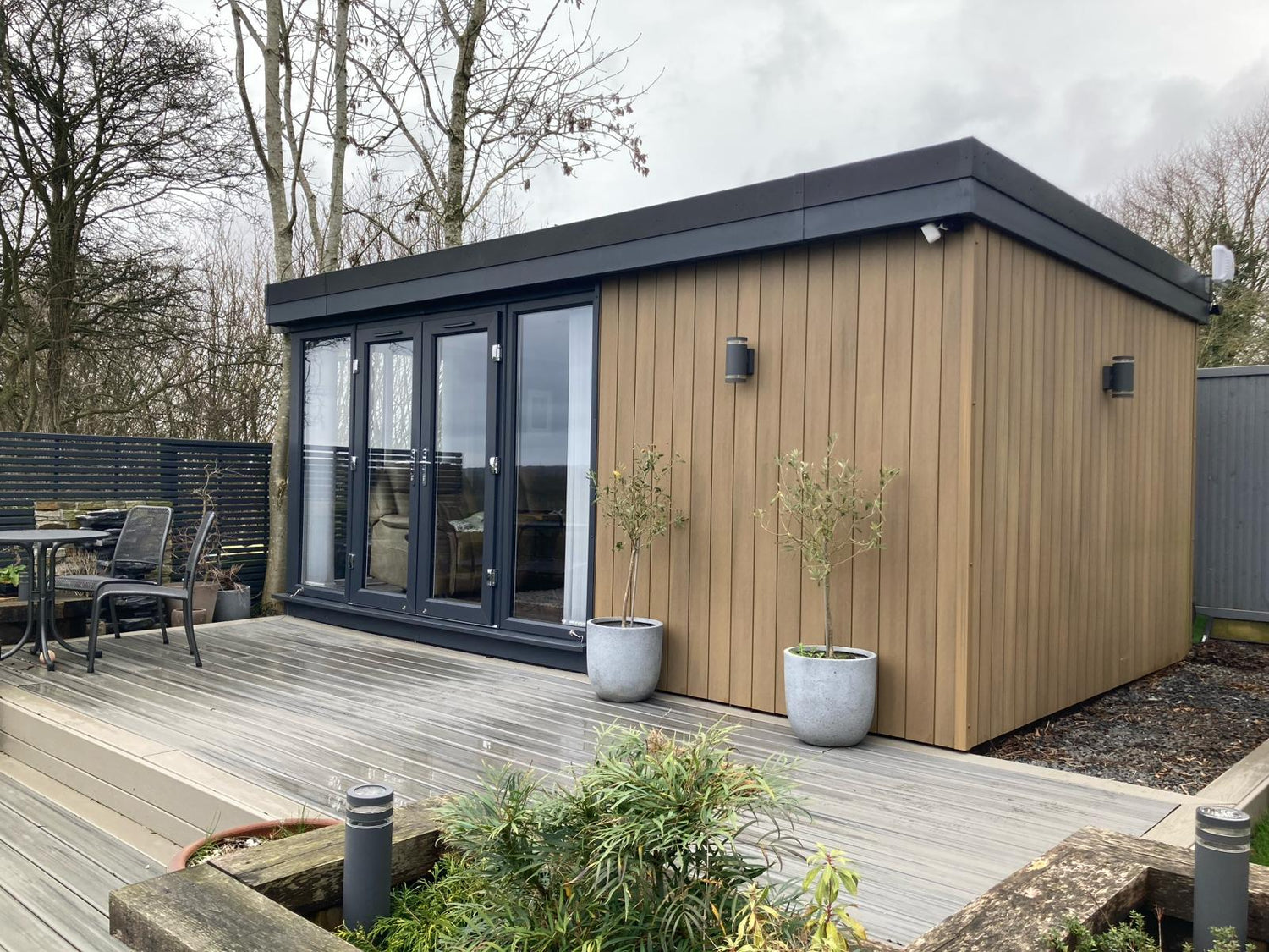Garden Room finished in Oak Composite Cladding, with French Doors and Long Fixed Panoramic Windows.
