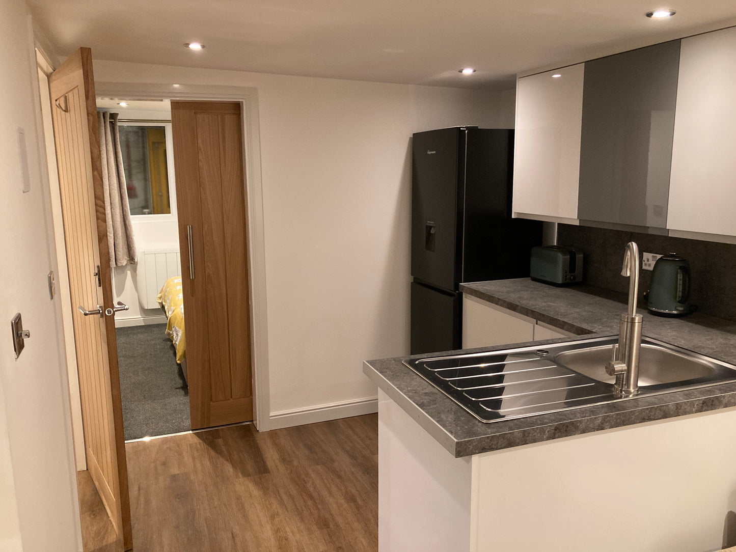 An open plan kitchenette leading through a sliding door into a double bedroom in a granny annexe