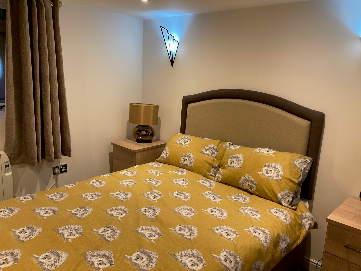 A double bed in a granny annexe bedroom with decorative wall lights and side tables