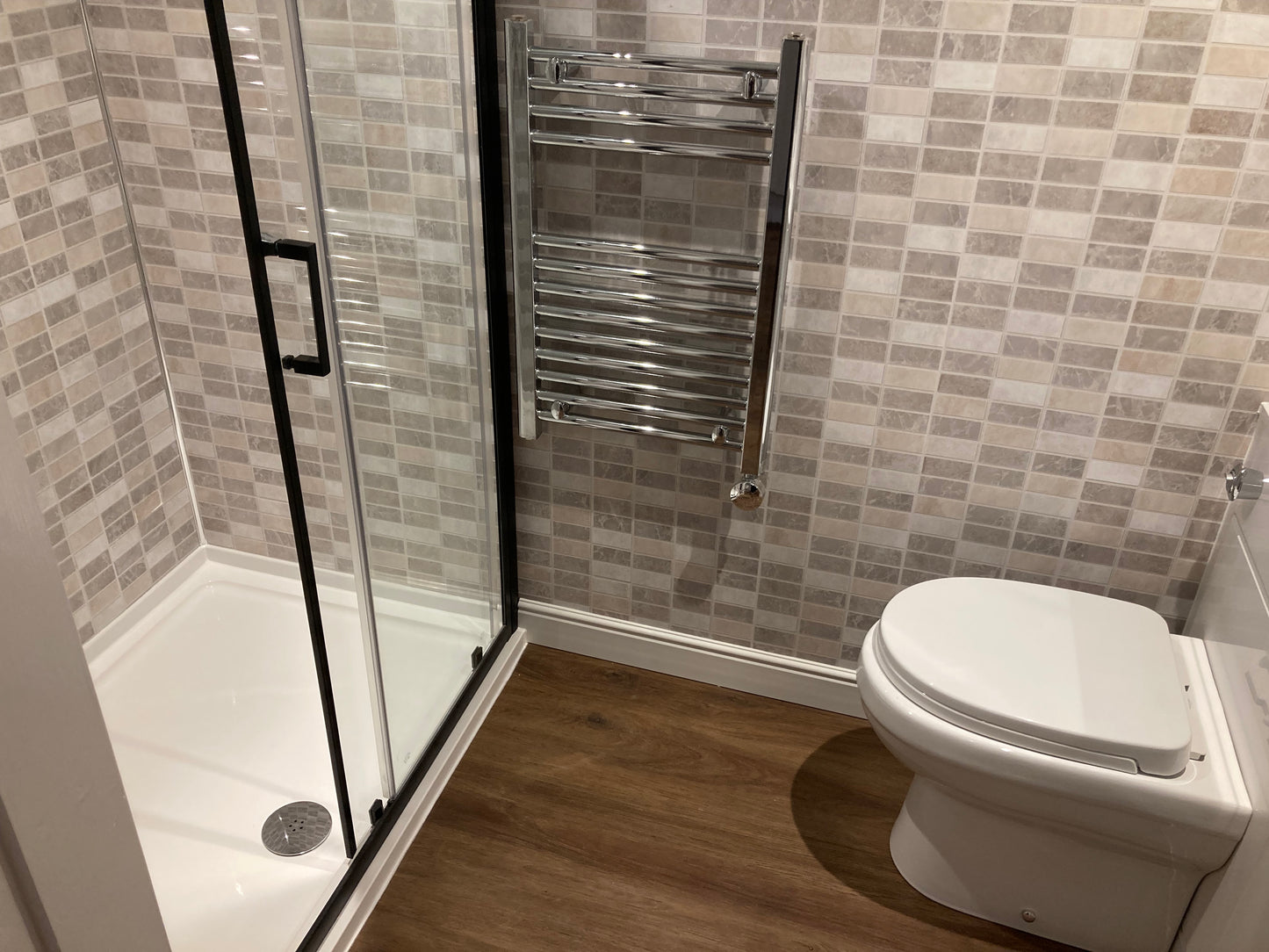 A fully fitted shower room and toilet with mosaic wall lining panels in a granny annexe