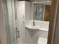 A fully fitted toilet and shower room with a sink and mirror in a granny annexe