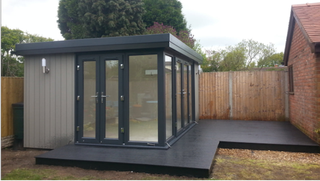 A Vista Style garden shed from Rubicon Garden Rooms with glass doors and a wood-fibre composite deck.