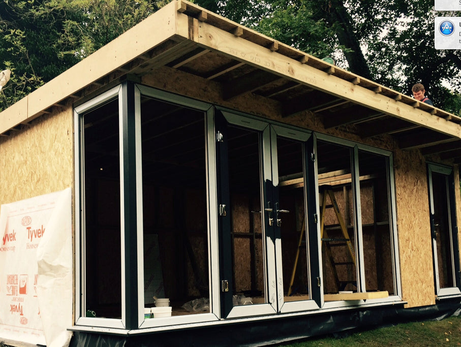 A wooden shed is being built in a yard.