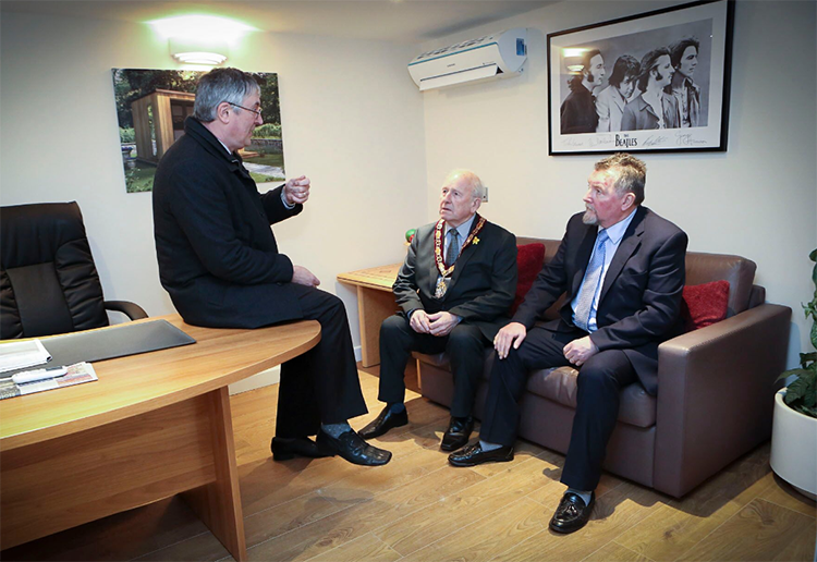 Three men sitting in an office.