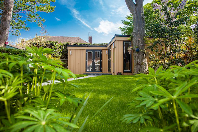 A garden shed in the middle of a grassy area.