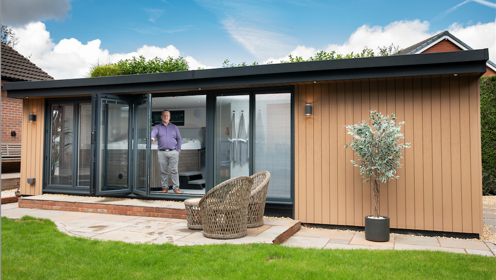 A man standing in front of a garden shed.