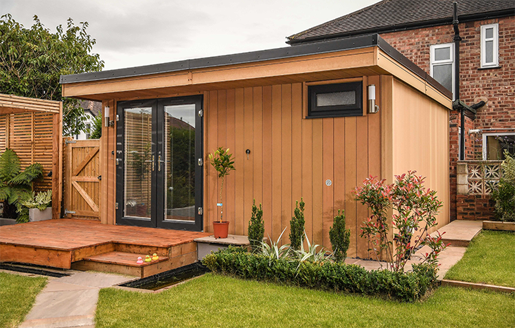 A garden shed in a backyard with a wooden deck.