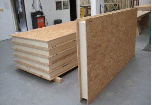 A sheet of plywood is sitting on a pallet in a workshop.