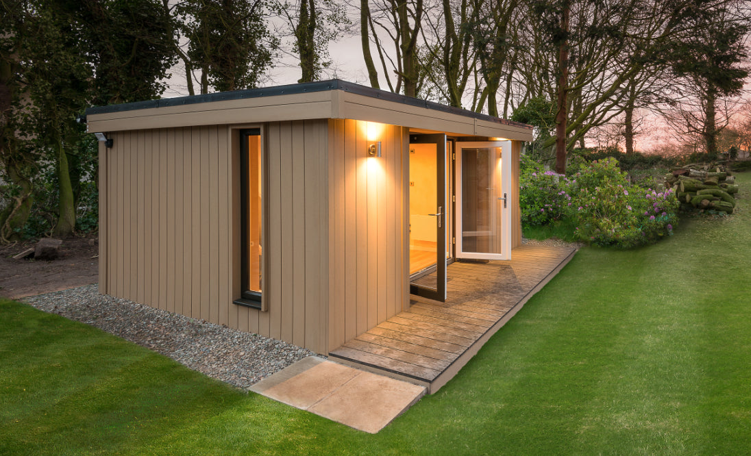 A small garden shed in the middle of a grassy area.