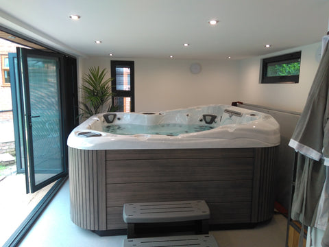 A large hot tub in a garden room with bifold doors