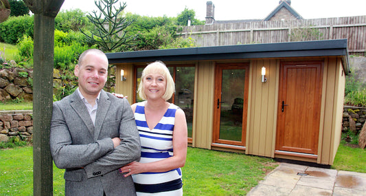 Two people standing by a garden room office in liverpool with a toilet 