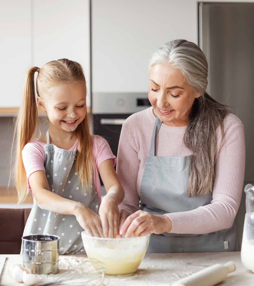 An older woman and a little girl are making cookies in the kitchen.