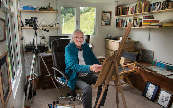 A man sitting in front of a painting easel in his rubicon garden art studio