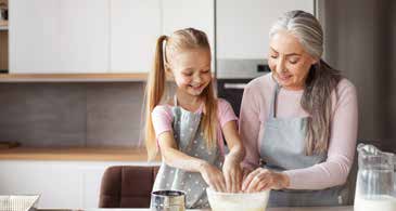 An older woman and a little girl making cookies in the kitchen.