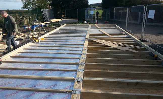 A man is working on the construction of a wooden deck.