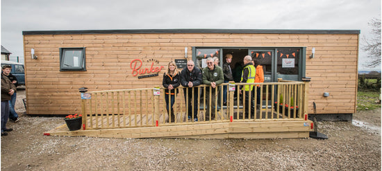 A group of people standing in front of a tiny house.