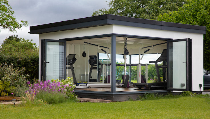 A gym in a backyard with a glass door.