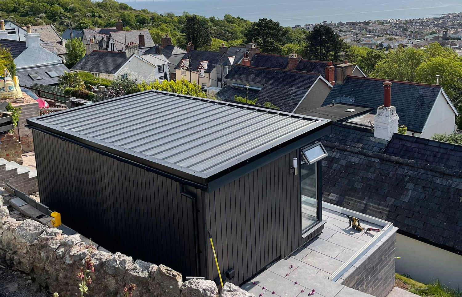 A black shed sits on top of a hill overlooking a city.