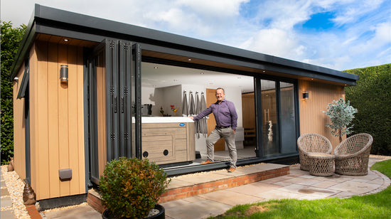 A man standing in front of a garden shed.