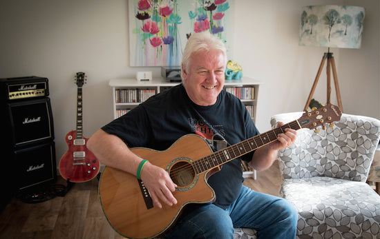 A man playing an acoustic guitar in his living room.