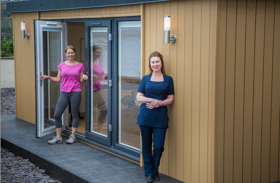 Two women standing in front of a small shed.