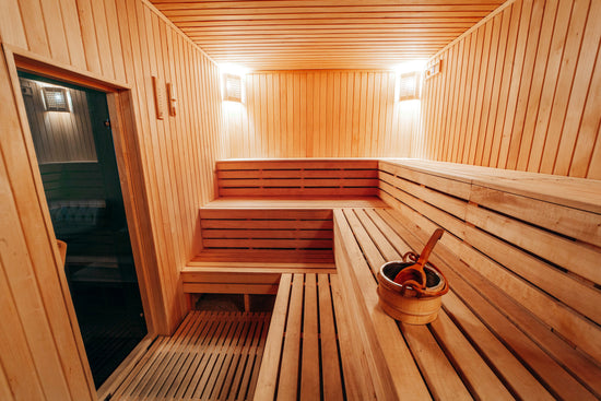 A sauna room with wooden benches and a bucket.