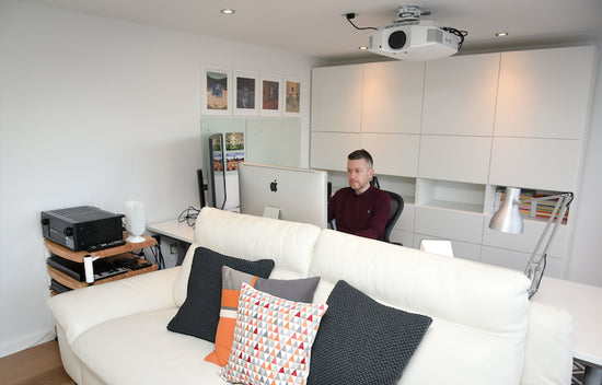 A white couch with a man sitting on it.