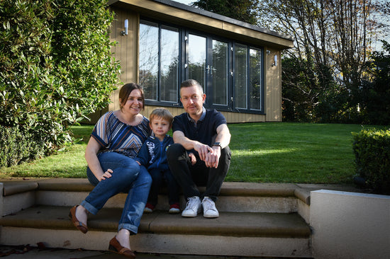 A man, woman and child sitting on steps in front of a house.